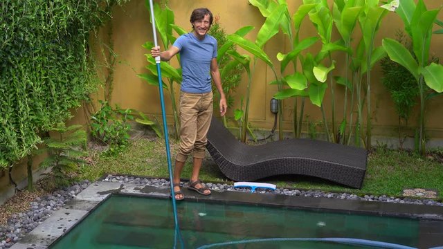 Young man professional swimming pool cleaner does pool cleaning service