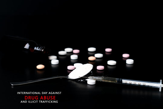 Different drugs - powder and pills and a syringe on a black background. Stop drug addiction. International Day against Drug abuse.  Copy space for text or advertisers.