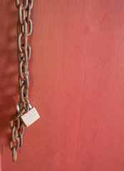 Fototapeta na wymiar the padlock with old chain on the red wooden door