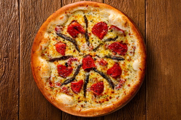 Pizza anchovy and dried tomato on wood background. Top view, close up. Traditional Brazilian Pizza.
