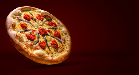 Pizza anchovy and dried tomato on black concrete background. Top view, close up. Traditional Brazilian Pizza.