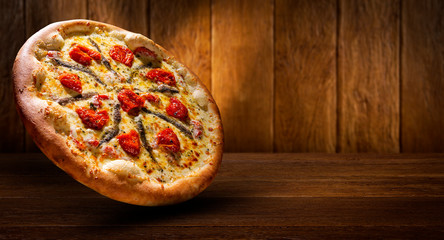 Pizza anchovy and dried tomato on wood background. Top view, close up. Traditional Brazilian Pizza.
