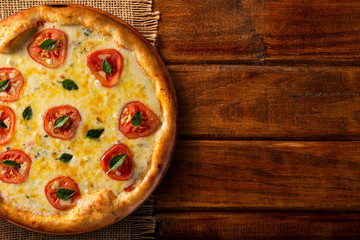 Obraz na płótnie Canvas Pizza Margherita on wood background, top view. Pizza Margarita with Tomatoes, Basil and Mozzarella Cheese close up. Traditional Brazilian Pizza.