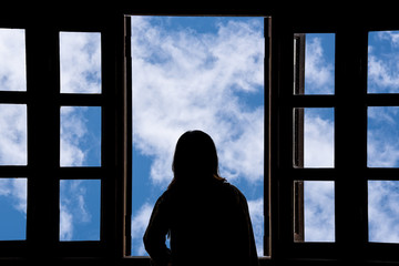 Silhouette woman looking out of window see blue sky and clouds.Freedom concept.