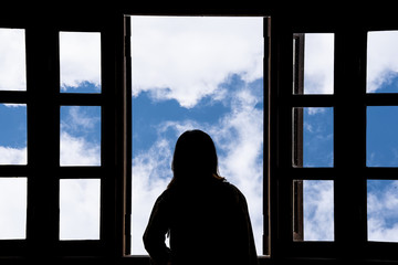 Silhouette woman looking out of window see blue sky and clouds.Freedom concept.
