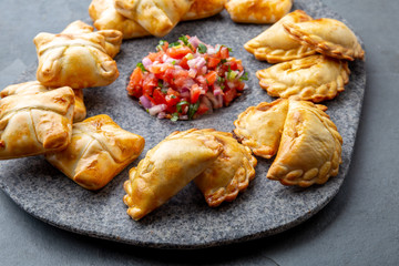 Different little cocktail EMPANADAS on stone plate with tomato sauce and guacamole . Gray background. Latin American and Spanish tipical food