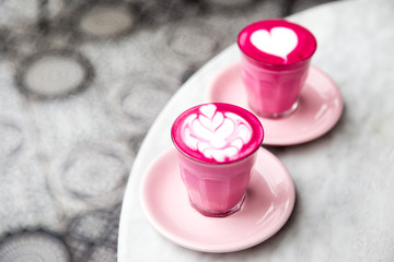 Two glasses of pink beetroot latte with beautiful latte art on marble table background. Trendy...