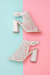 Summer shoes made of white leather on blue and pink background. Flat lay.