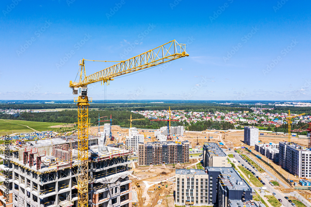 Wall mural yellow crane near multistorey apartment building under construction. aerial view