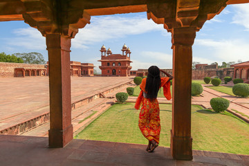 Fatehpur Sikri red sandstone architecture with view of woman tourist posing at the ancient fort...