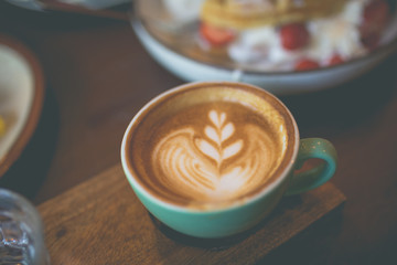 Latte hot coffee with foam milk art on a wooden table