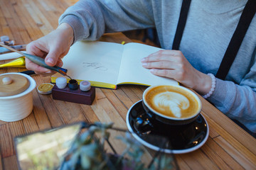 Close up of hands woman calligrapher writes something on notepad. Inscribing ornamental decorated letters. Calligraphy, lettering, graphic design handwriting, creation concept.