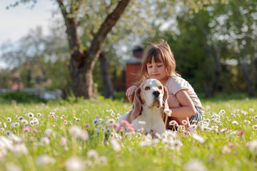 Happy little girl playing with dog in garden.