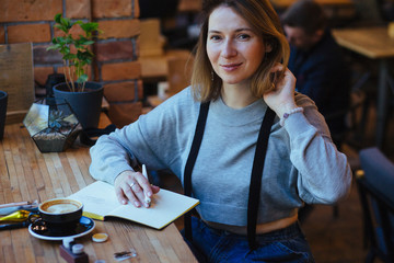 Female calligrapher dreaming in cafe. Portrait of mature business woman drinking coffee writing...