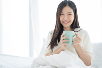 Young Asian woman drink coffee on bedroom morning
