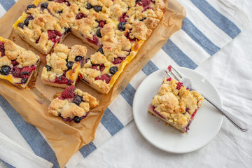 crumble cake in a baking form and pieces of the cake on a table