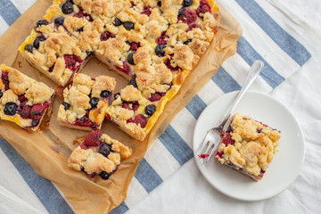 crumble cake in a baking form and pieces of the cake on a table