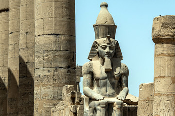 Fototapeta na wymiar Egypt Luxor Temple. granite Statue of Ramesses II seated in front of columns