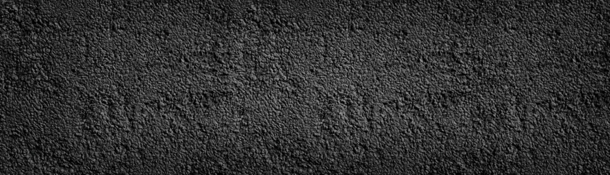 Black painted stone wall wide texture. Dark coarse pebbledash panoramic background