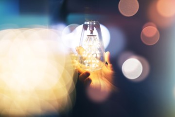 Obraz na płótnie Canvas lights bulb with hand on blurred background