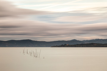 Obraz na płótnie Canvas Beautiful long exposure view of Trasimeno Lake (Umbria, Italy), with still water and moving clouds
