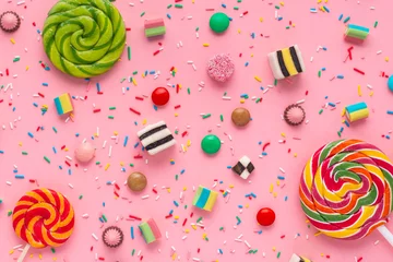 Fototapeten flat lay of festive background with assortment of colourful caramel candies with jelly and sprinkles over pink © Alisa
