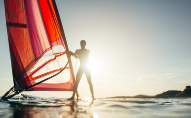 Windsurfer on windsurf board on the sunset sea, copy space