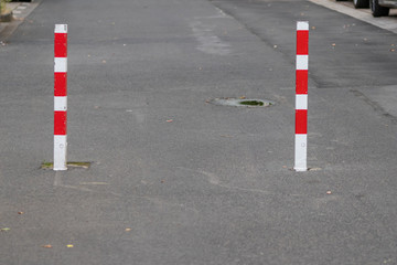 Rot weiß gestreifte Pfeiler hindern Autos an der Durchfahrt einer Straße, lassen jedoch...