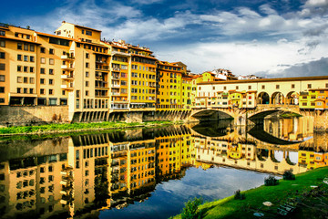 Naklejka premium Old bridge Ponte Vecchio with colourful buildings houses and its reflection in the river Arno in Florance, Tuscany, Italy. April 2012