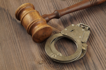 Wooden judge gavel and black handcuffs on table
