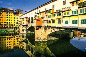 Fototapeta na wymiar Old bridge Ponte Vecchio with colourful buildings houses and its reflection in the river Arno in Florance, Tuscany, Italy. April 2012