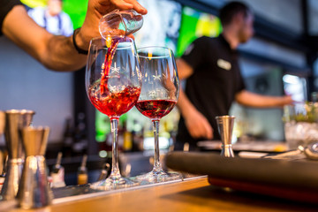 glasses of cocktails on the bar. bartender pours a glass of sparkling wine with Aperol.