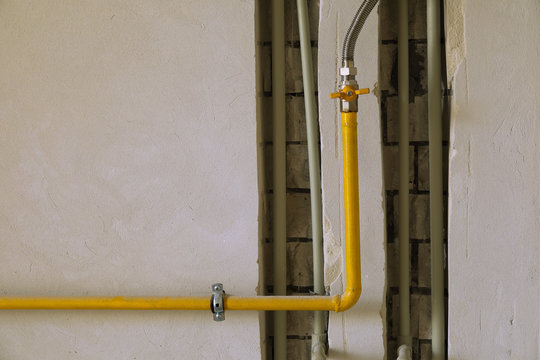 Yellow Gas Pipe On Residential House Wall.