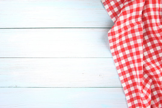 Red checked picnic towel cloth on blue wooden empty space background.