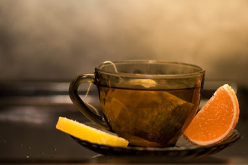 Transparent cup of tea with a lemon and orange marmelade slices.