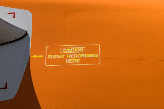yellow caution sign on airplane fuselage "caution flight recorders here"