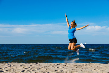 Young woman running, jumping on beach