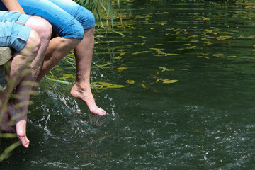 Zwei Damen kühlen sich ab und planschen mit den Füßen im Wasser.