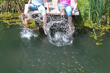 Zwei Damen kühlen sich ab und planschen mit den Füßen im Wasser.