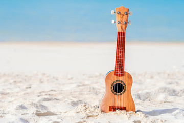 Music concept. guitar is placed on the beach isolate on blue sea background.