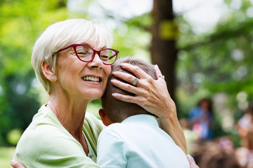 Loving senior woman embracing her grandchildren with a cheerful smile on her face