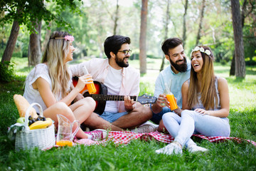 Happy friends in the park having picnic on a sunny day.