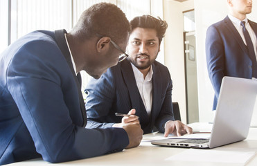 A team of young businessmen working and communicating together in an office. Corporate businessteam and manager in a meeting.