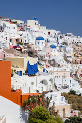 Fototapeta premium beautiful Oia town on Santorini island, Greece. Traditional white architecture and greek orthodox churches with blue domes over the Caldera, Aegean sea. Scenic travel background