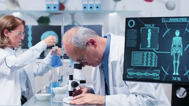 Medium shot of mature scientists working in busy modern laboratory