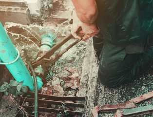 plumber working repair the broken pipe with Adjustable Wrenches or Locking Pliers in hole ditch at...