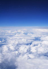Plane view of clouds in the bright blue sky on a summer day and visible stars. Fluffy clouds backdrop with warm sunlight.