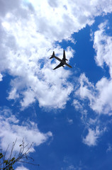 Airplane taking off from nearby airport, flying towards clouds in sky.