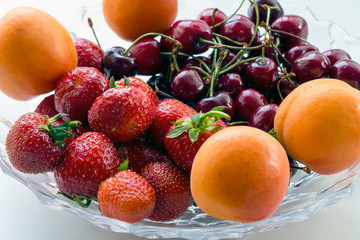 cherries, strawberries, apricots - berries and fruits in a vase. seasonal vitamins
