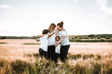 Happy family hugging in the field and smiling. Family in a sunset